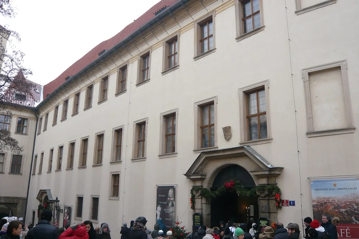 Die lange helle Fassade des Lobkowicz-Palastes in der Jiřská-Straße mit ihrem steinernen Eingangsportal.
