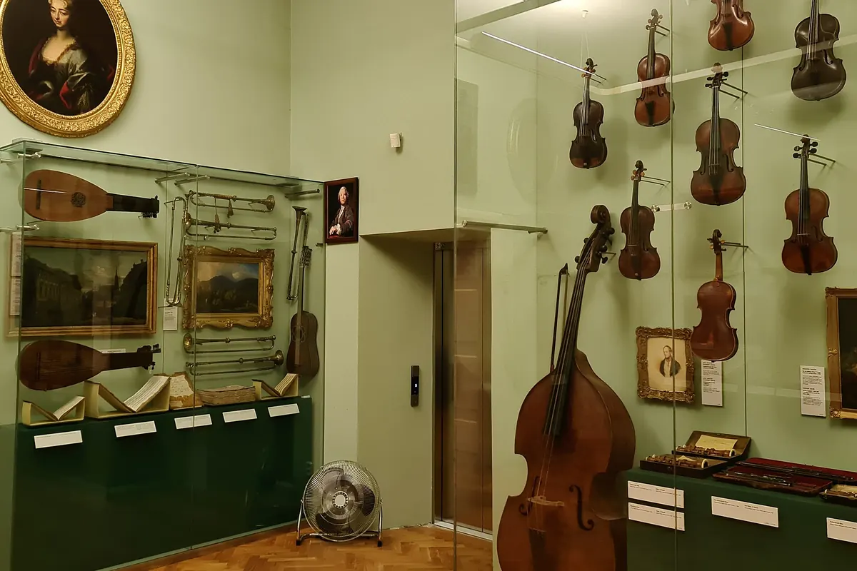 Ein Museumsraum mit Lauten, Violinen und einem Kontrabass an den Wänden und in Glasvitrinen.