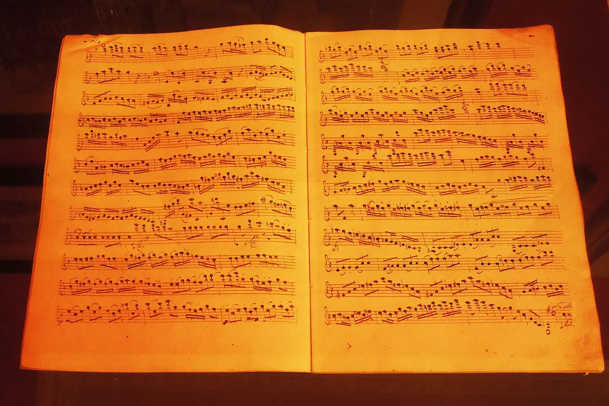 Eine aufgeschlagene Doppelseite einer handschriftlichen Partitur im orangefarbenen Licht, aus den Lobkowicz Collections.